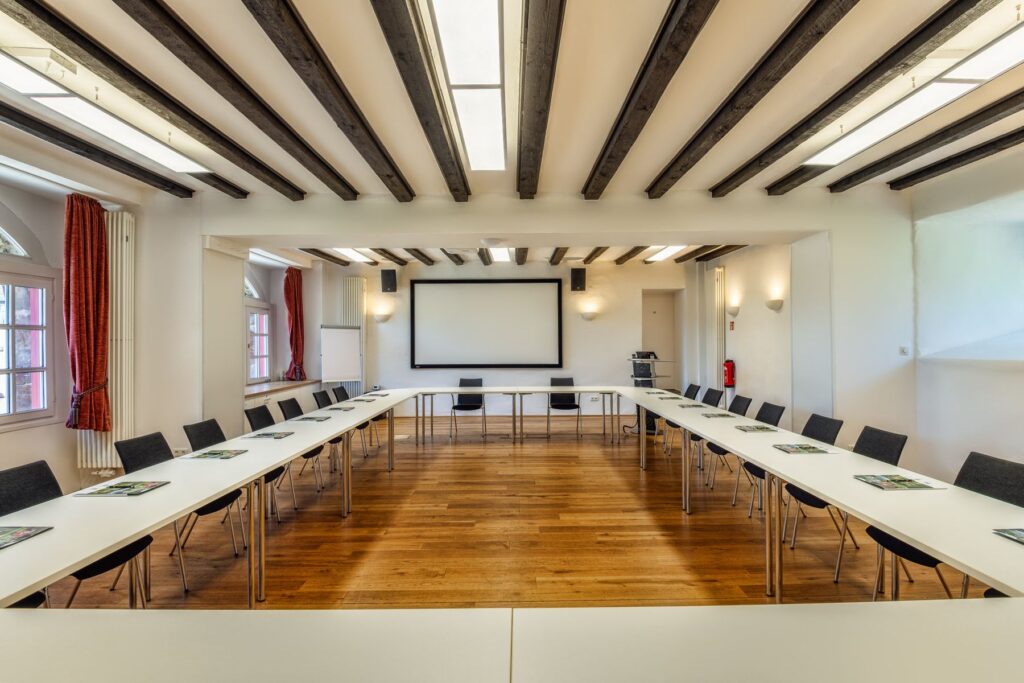 Sala Artur Winkelmann con pantalla y mesas en forma de U